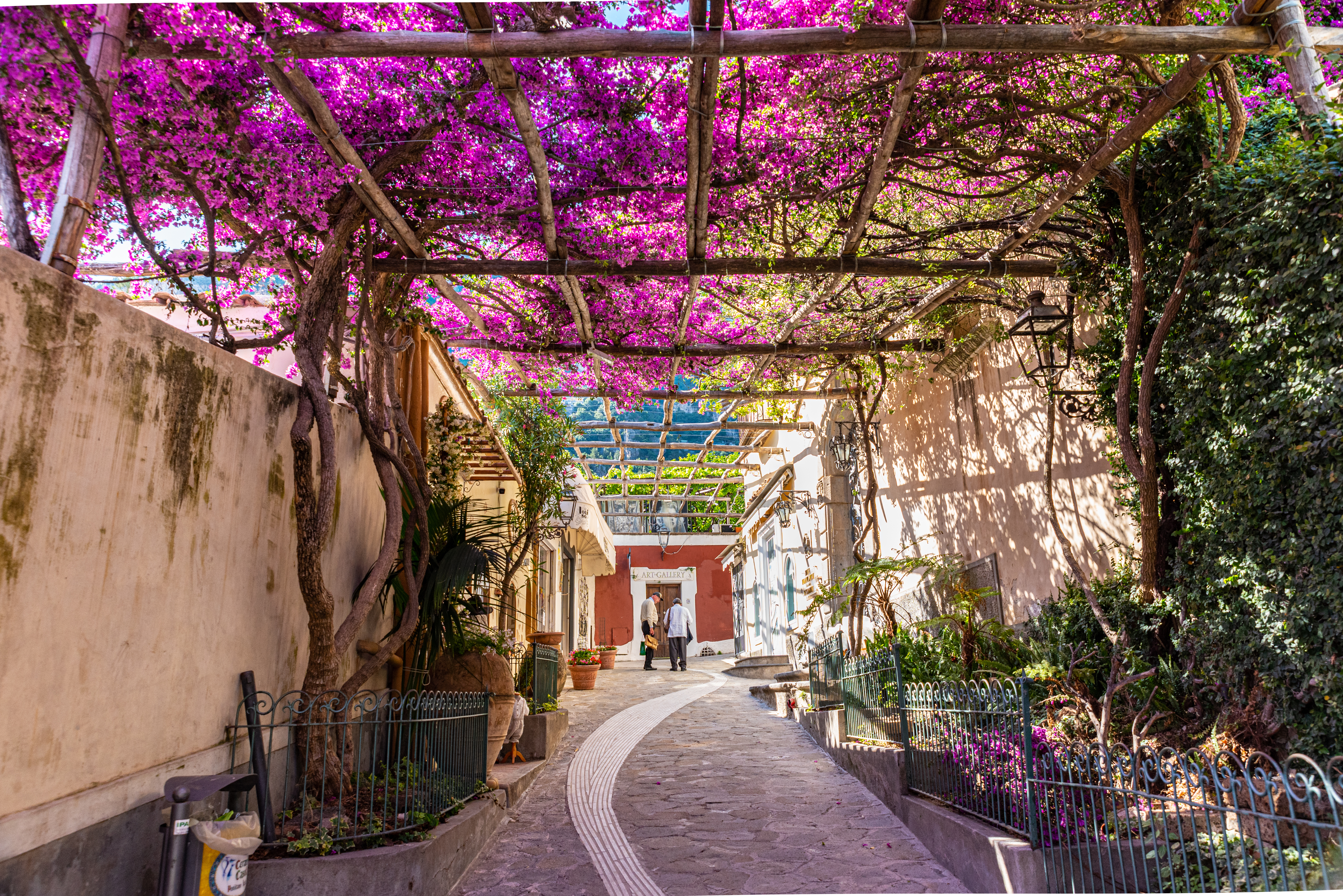 Illuminated blue lanterns hang under a pergola at dusk, creating a warm, inviting ambiance.